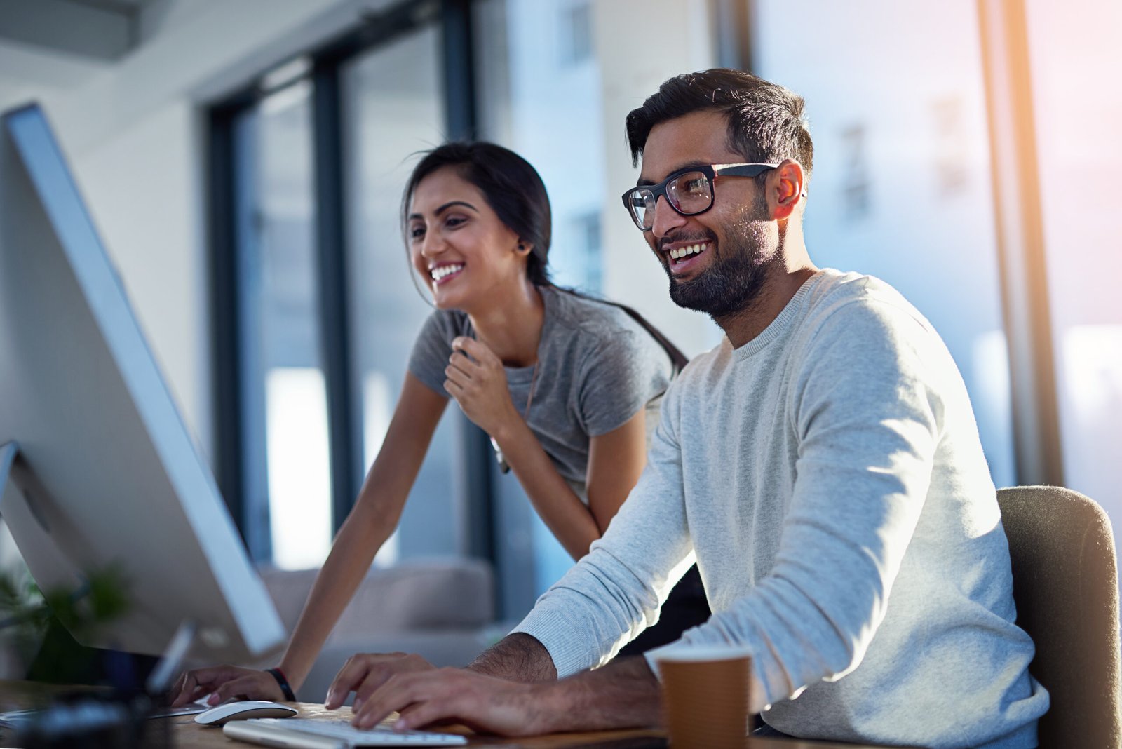 About share what makes you happy. shot of two young coworkers using a computer together at work.